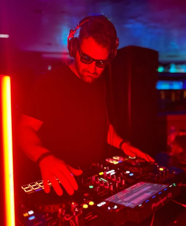 Gonzalo Bigiolli mezclando música en la cabina con iluminación roja